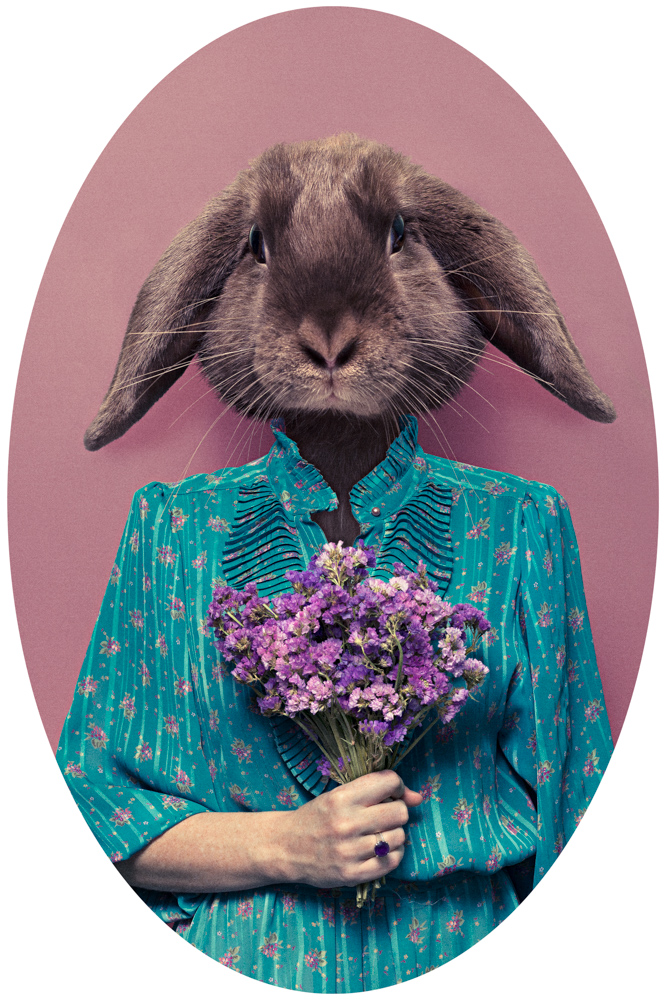 girl in flowerly blue dress with a rabbit head and holding flowers