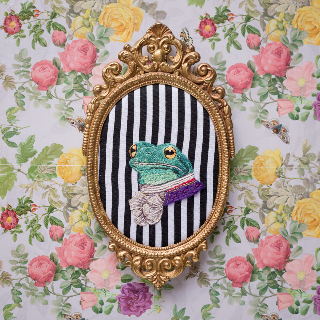 Embroidered Portrait of Frog dress in Victorian clothes within a gold frame